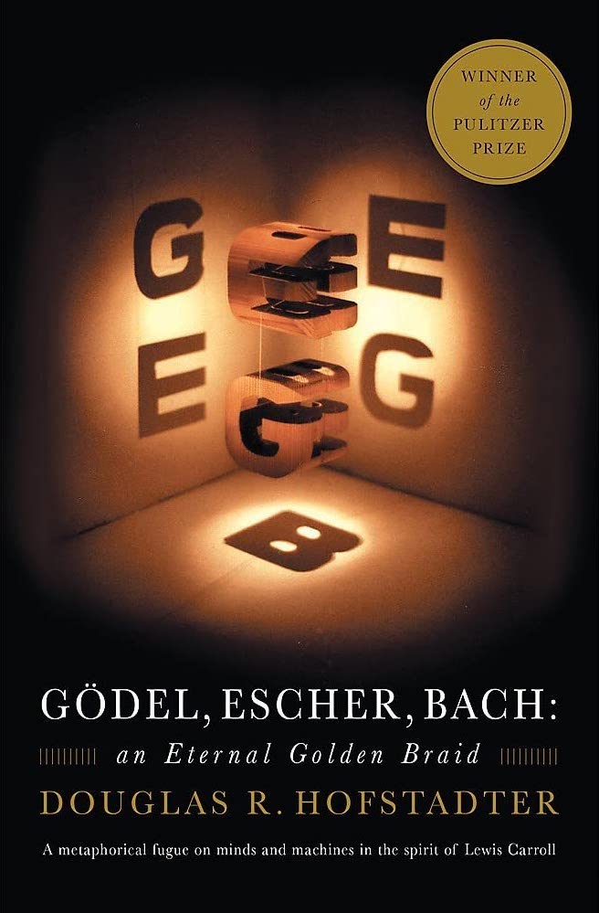 The cover of Douglas Hofstadter's book, Godel, Escher, Bach. Two intricately carved blocks hang suspended above one another. Lights shining through them cast shadows of a G and E to the left, an E and G to the right, and a shadow B below from a light shining directly down through both blocks.